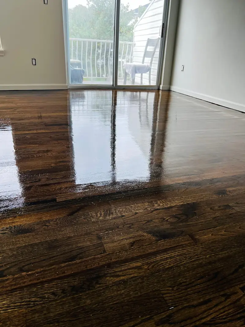 Dark-stained hardwood floor with a high-gloss finish in front of a sliding glass door