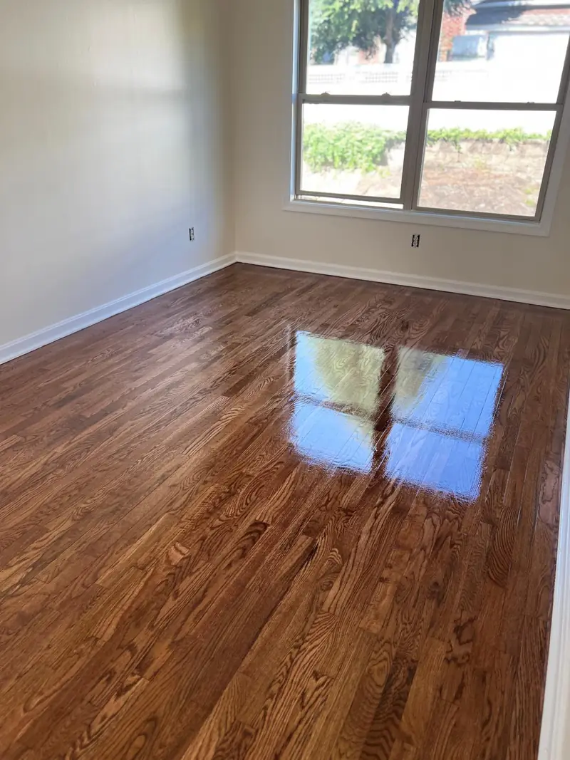 Refinished hardwood floor with a high-gloss finish reflecting window light