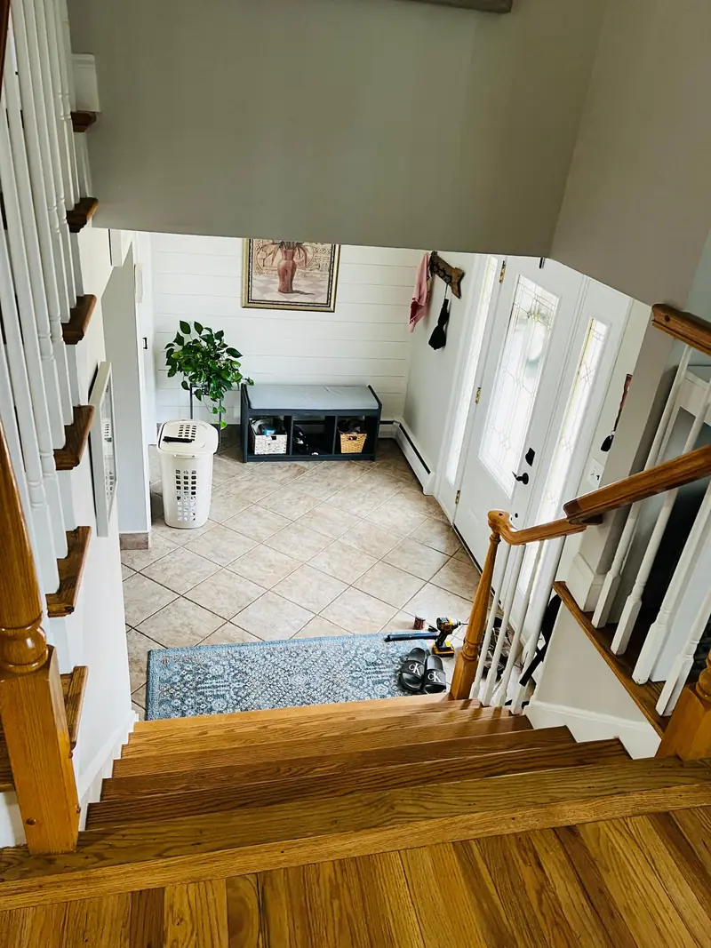 Refinished hardwood stair landing overlooking the entryway
